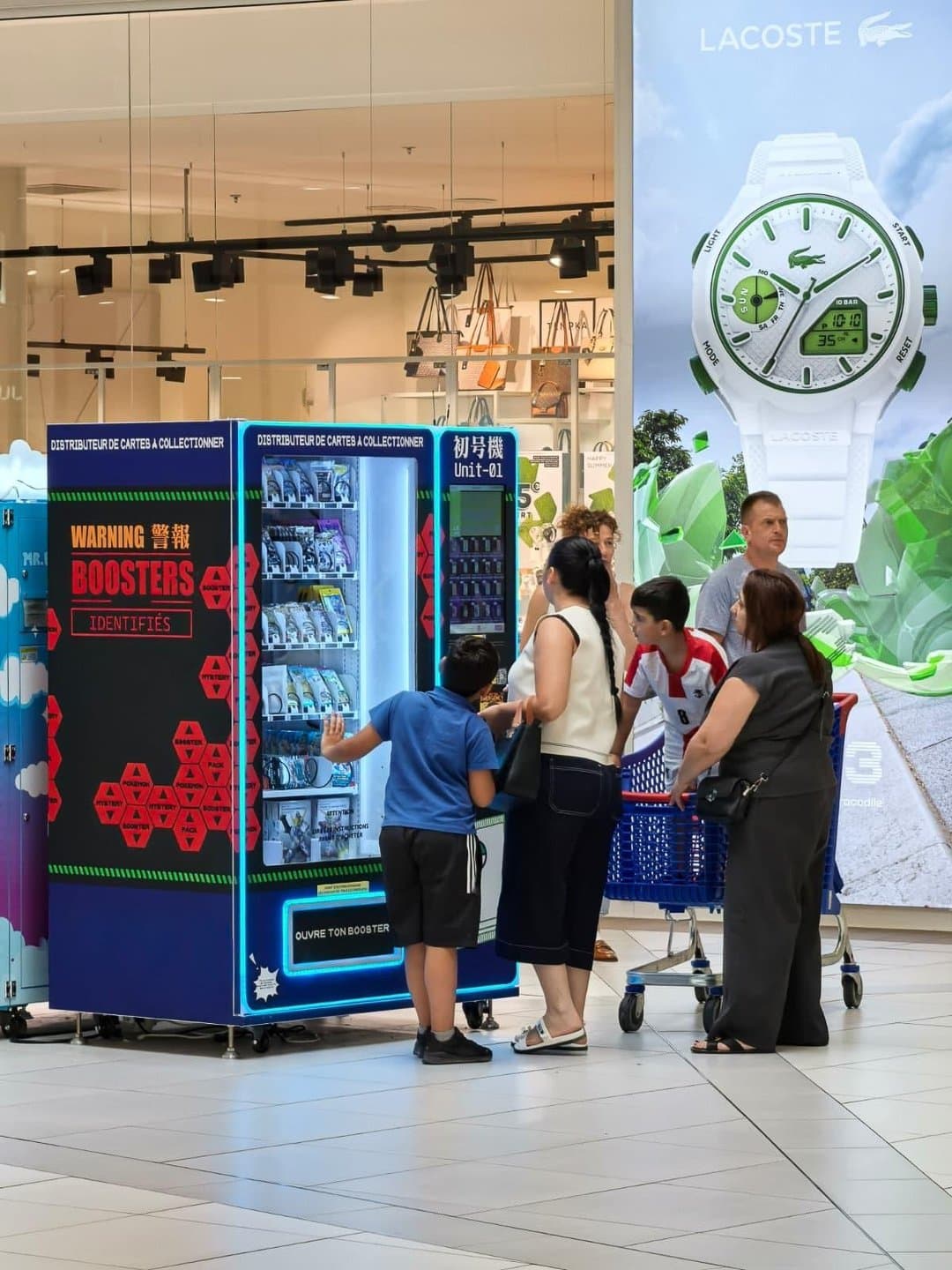 Une famille devant un distributeur Gang de Cartes dans un centre commercial
